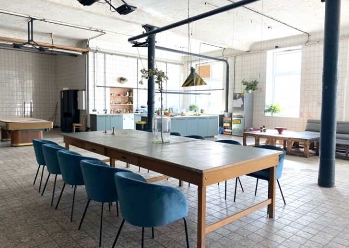 Nudelfabrik von Innen als großer Gemeinschaftsraum mit Tisch in der Mitte und Küche
