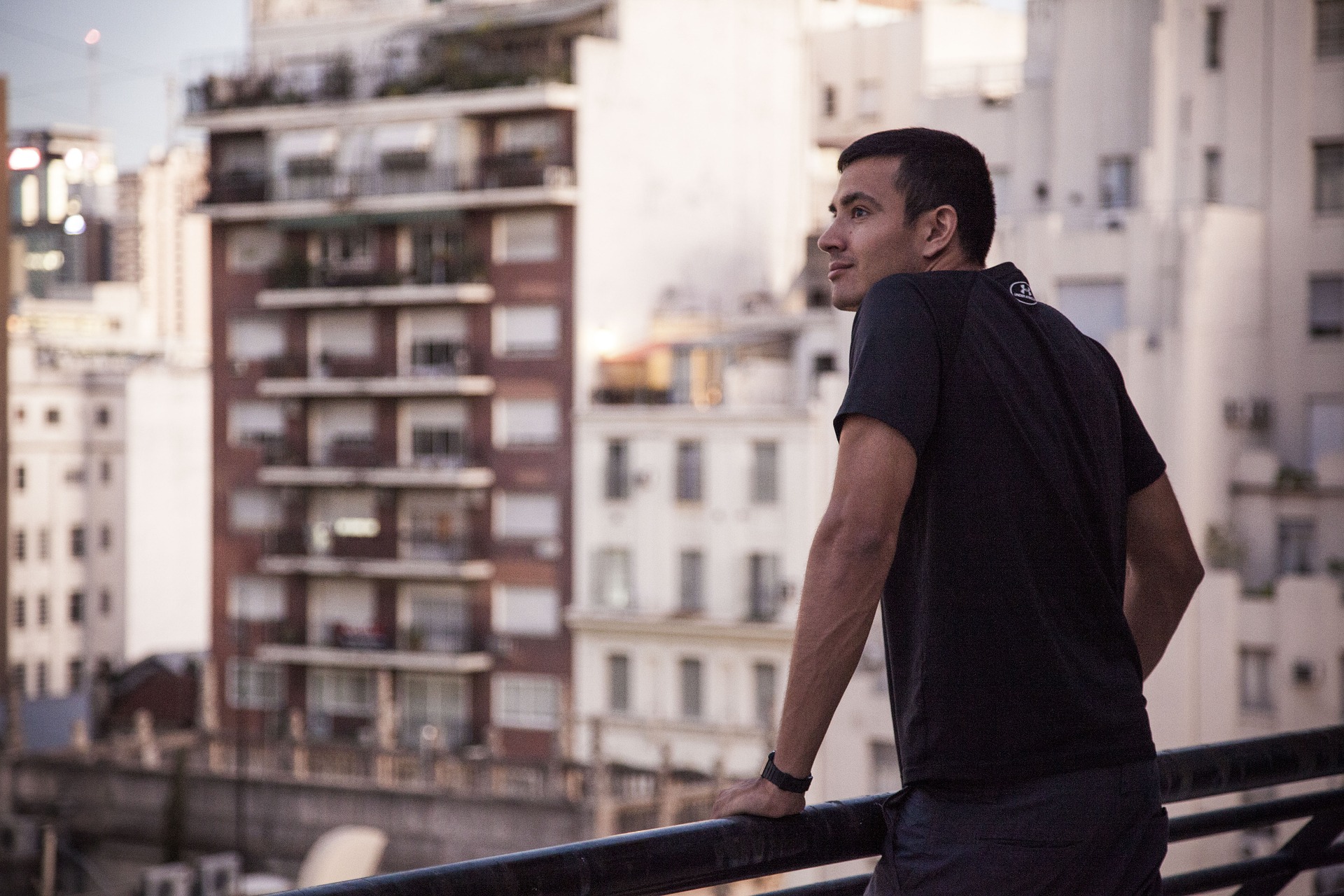 Zukünftig lieber Urlaub auf Balkonien? ©Pixabay Mann steht am Balkongeländer und blickt auf die Stadt