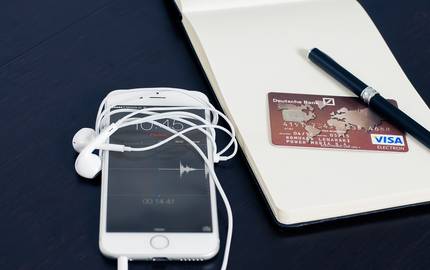 Smartphone und Kreditkarte auf Tisch mit Notizblock und Stift