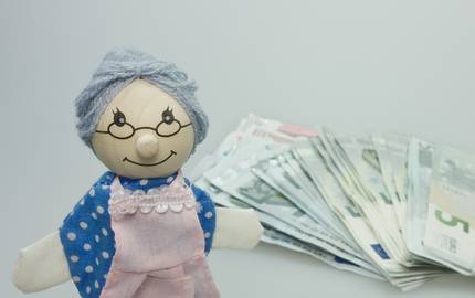 Puppe als oma mit Geldscheinen im Hintergrund