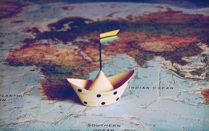 Papierschiff auf Weltkarte