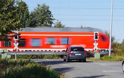 Schneller unterwegs: Durch den Schienenausbau soll die Reisezeit verkürzt werden. Zug saust an den an der Schranke wartenden Autos vorber