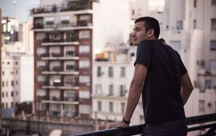 Zukünftig lieber Urlaub auf Balkonien? Mann steht am Balkongeländer und blickt auf die Stadt