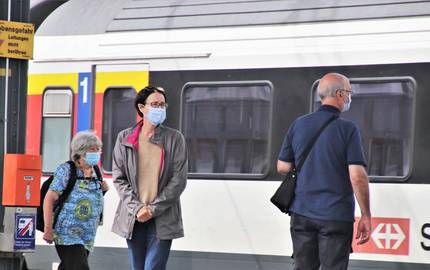 Reisende mit Mund-Nasen-Schutz am Bahnhof
