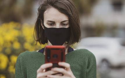 Frau mit Maske und Smartphone