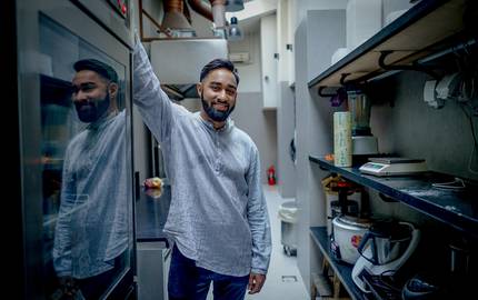 männlicher Mitarbeiter steht lächelnd in der Küche