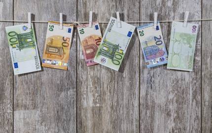Euroscheine an Wäscheklammern vor Holzwand