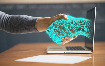 digitale Hand aus Laptop reicht Person die Hand.