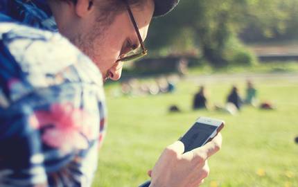 Mann mit Smartphone auf Wiese