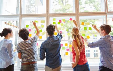 Menschen an einer Pinnwand mit Notizzetteln